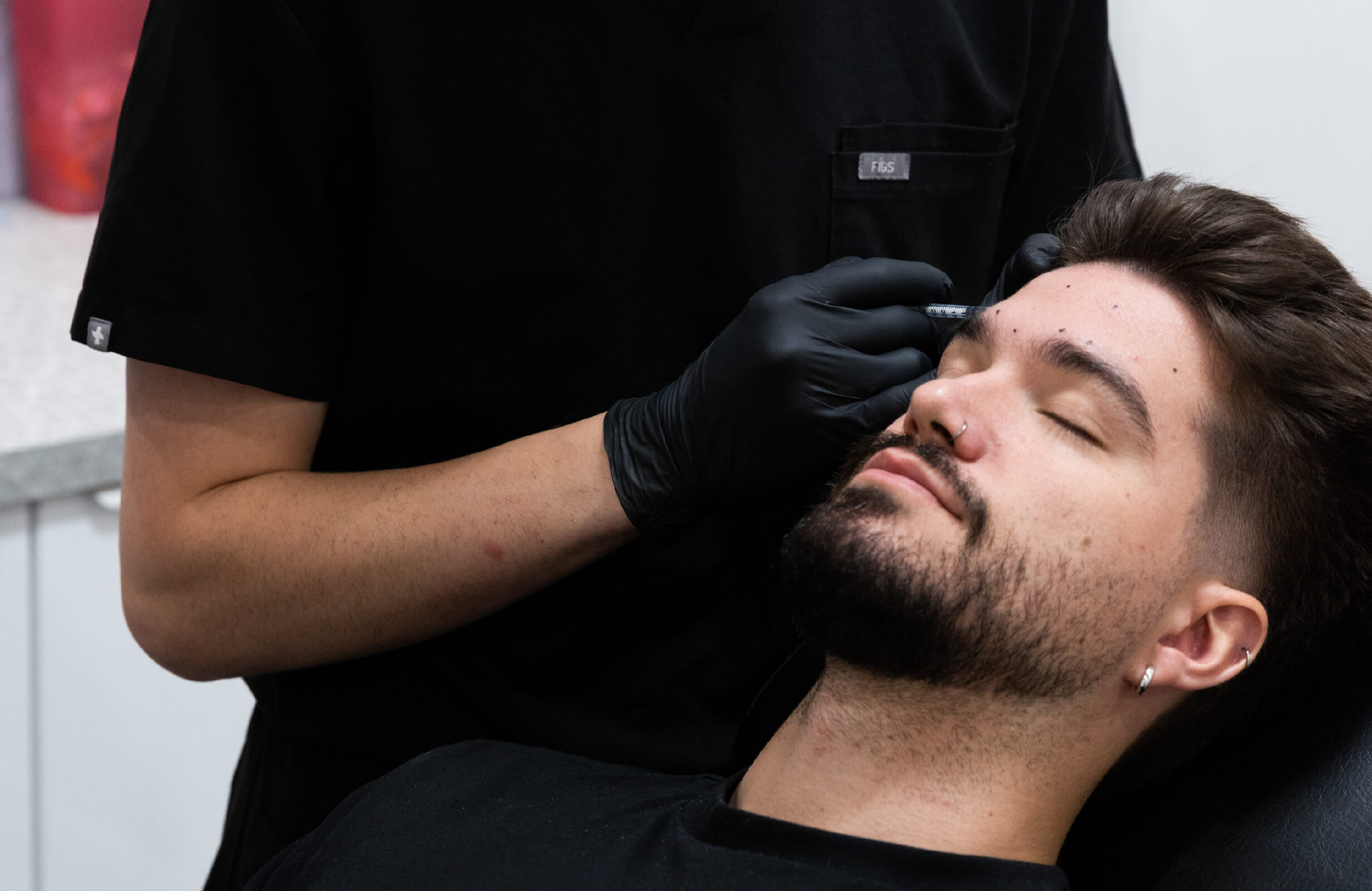Injection de neuromodulateurs Brotox dans la zone du front chez un homme pour atténuer les rides d’expression et lisser le regard.