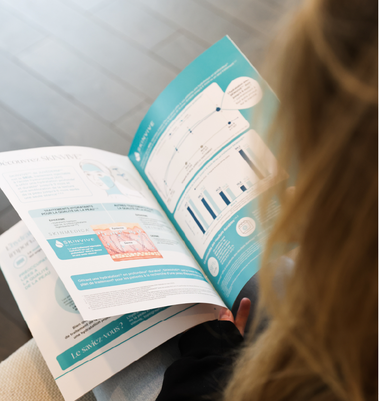 Femme consultant une brochure d’information sur le traitement Skinvive par Juvéderm, axé sur l’hydratation et l’amélioration de la qualité de la peau.